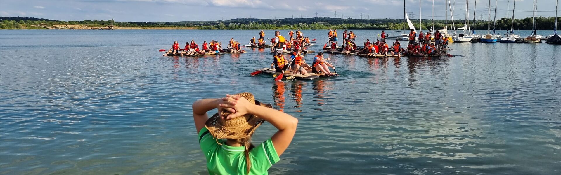 Teamtrainerin (vorne) und Gruppe (hinten) beim Floßbau Teamevent/Teambuilding/Betriebsausflug am Hardtsee bei Heidelberg.