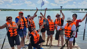 Eine überglückliche Gruppe auf eigenem Floß beim Floßbau Teamevent/Teambuilding/Betriebsausflug von bo events am Hardtsee zwischen Heidelberg und Bruchsal.