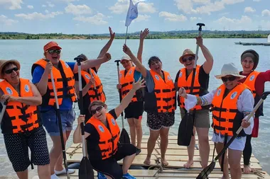 Eine überglückliche Gruppe auf eigenem Floß beim Floßbau Teamevent/Teambuilding/Betriebsausflug von bo events am Hardtsee zwischen Heidelberg und Bruchsal.