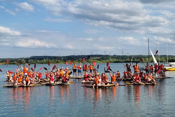 Eine Gruppe von Personen nach erfolgreichem Teamevent Floßbau am Hardtsee zwischen Heidelberg und Bruchsal.